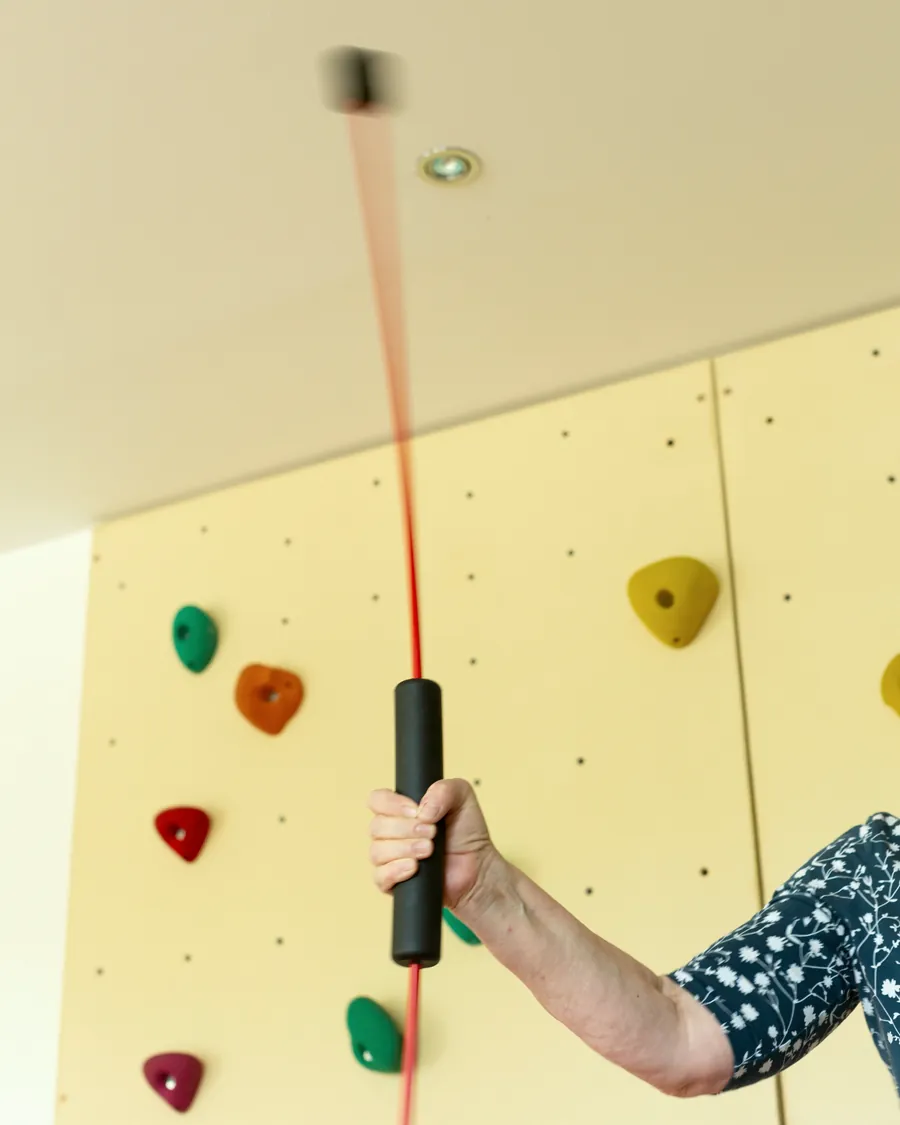 Eine Hand greift den Seilzug vor der therapeutischen Kletterwand