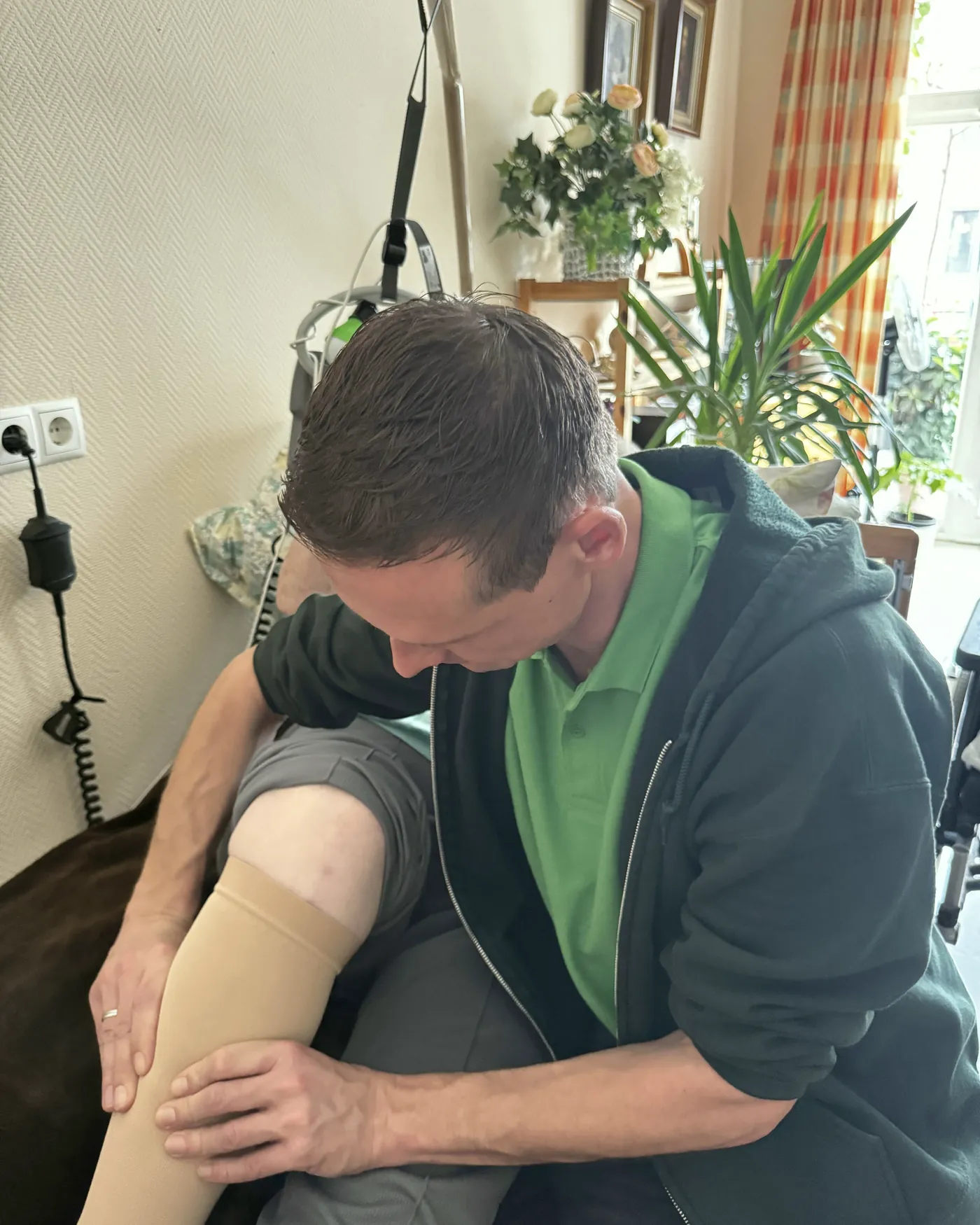 Therapeut prüft den Kompressionsstrumpf am Unterschenkel einer Patientin