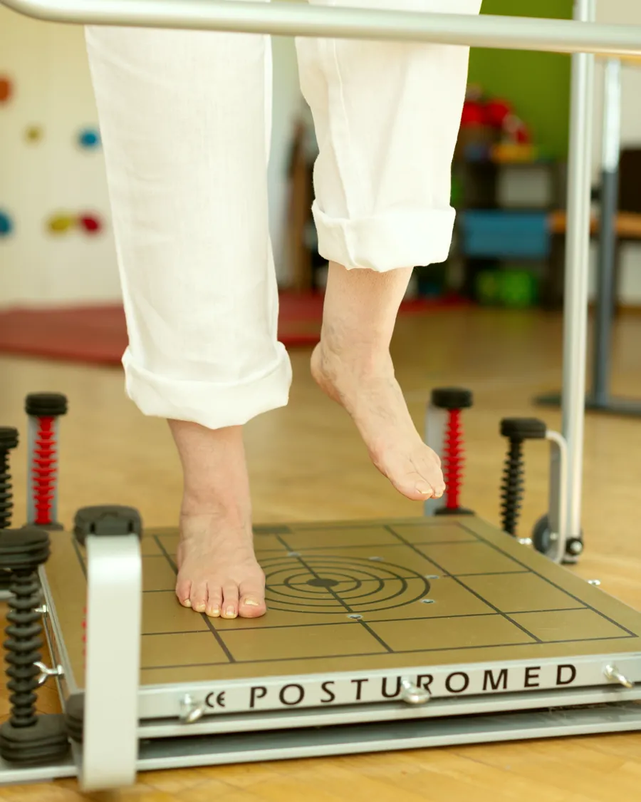 Eine Patientin steht auf einem Bein auf dem Posturomed